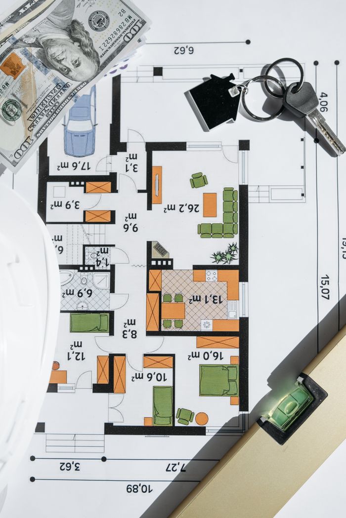 Overhead view of a house floor plan with keys and cash, symbolizing real estate investment.
